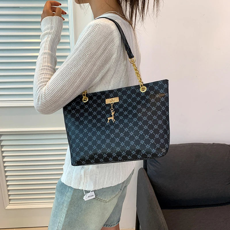 Large leather tote bag for women with structured shape and gold chain straps